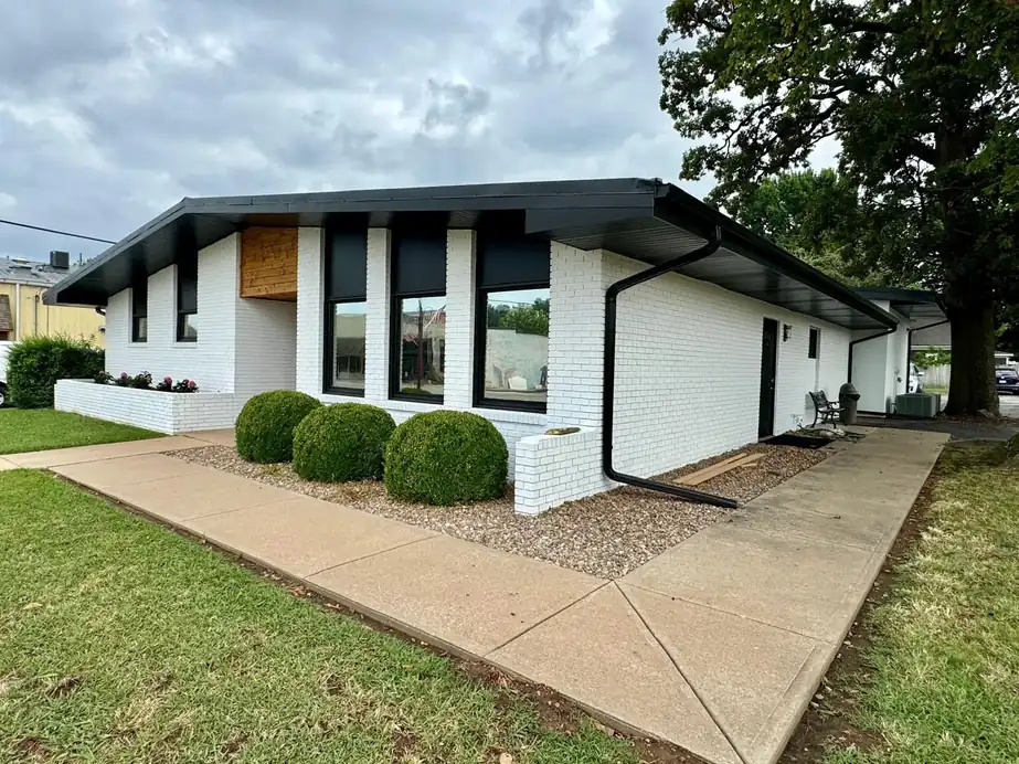 White-finished brick office front with black window surrounds and a cedar entry in Northwest Arkansas