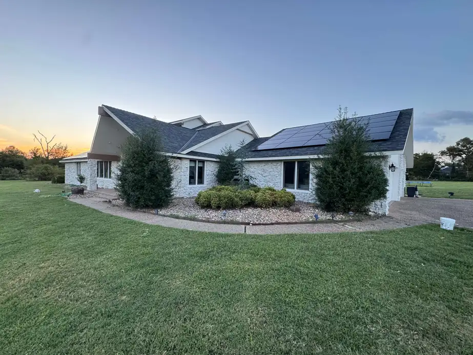 White-painted stone ranch home at dusk after an exterior repaint by Quality Pro Painting